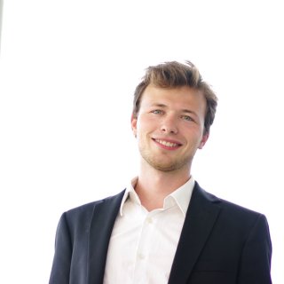 Brown-haired man in a suit laughs into the camera