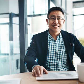 Man sitting at a table with a tablet and his coffee